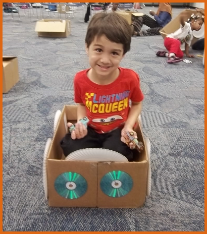 child playing in a cardboard box decorated to look like a car