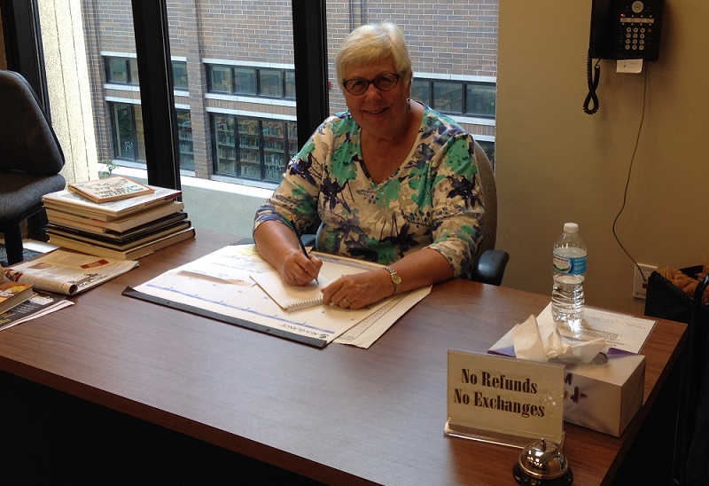 A smiling volunteer at the book sale room desk