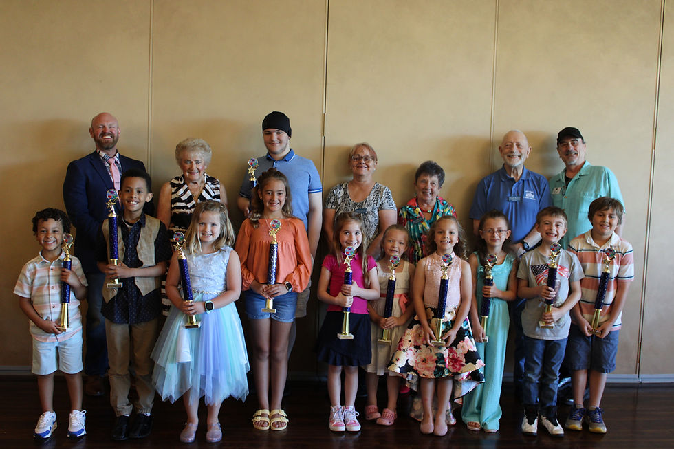 A row of kids holding trophies with Foundation board members in the back