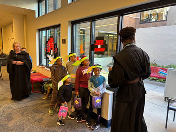 Kids wearing paper Yoda ears lined up in front of a librarian in a Jedi robe