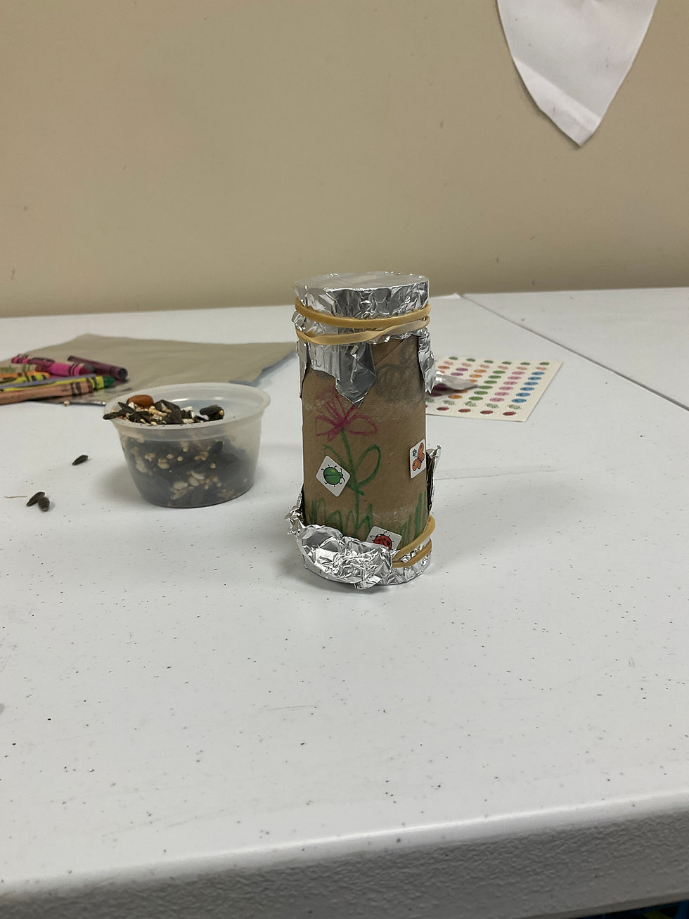 The finished project: a decorated cardboard tube with both ends covered with foil caps held on with rubber bands