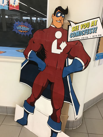Cardboard standee of a superhero with a library icon on the chest