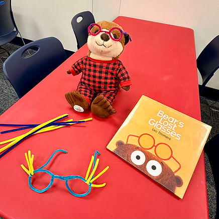 A stuffed otter wearing pipe cleaner glasses pictured with the book and the craft and some spare pipe cleaners