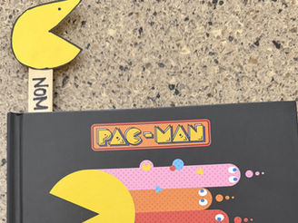 The book shows pac man zooming away with four colorful ghosts trailing behind. The bookmark craft is poking out the top.