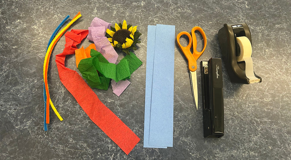 Supplies: pipe cleaners, paper streamers, a fake sunflower, paper strips, scissors, stapler, and tape