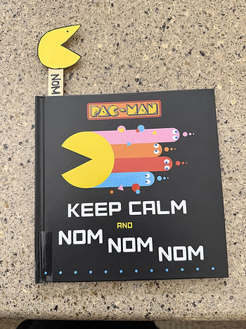 The book shows pac man zooming away with four colorful ghosts trailing behind. The bookmark craft is poking out the top.