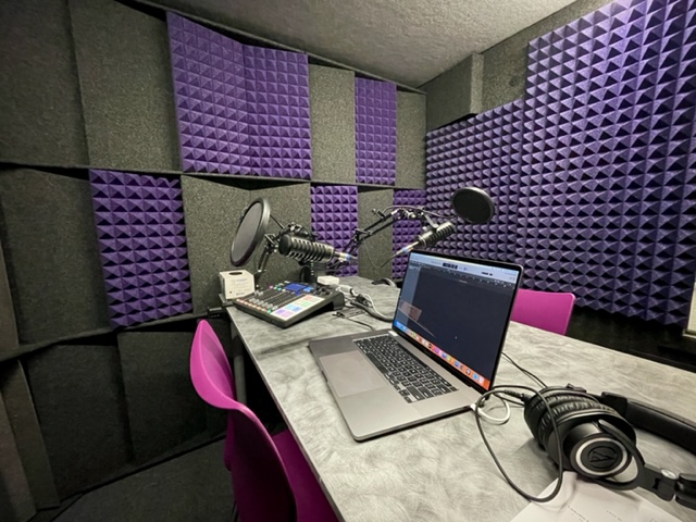 The interior of the sound booth, with sound board, mic, and laptop open showing mixing software