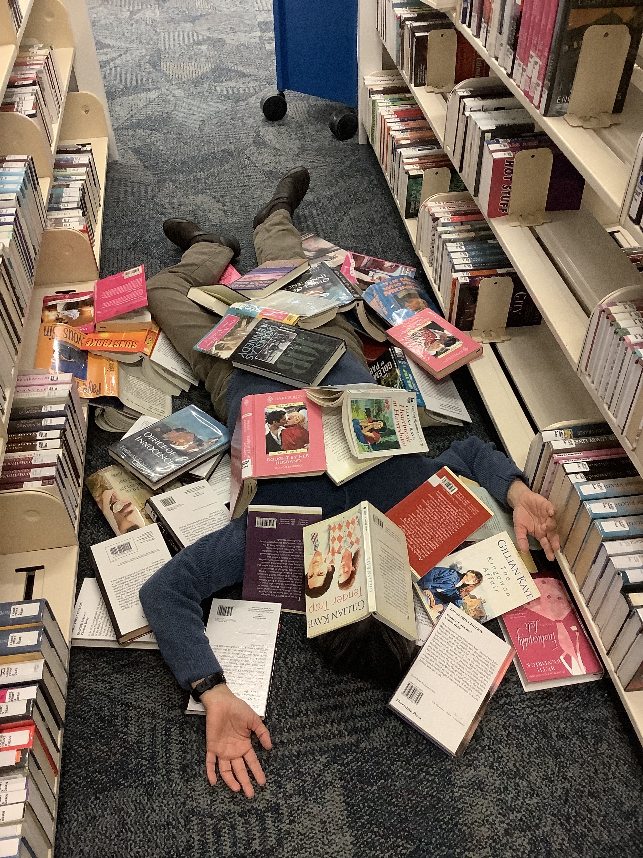 a person lying sprawled underneath many many books