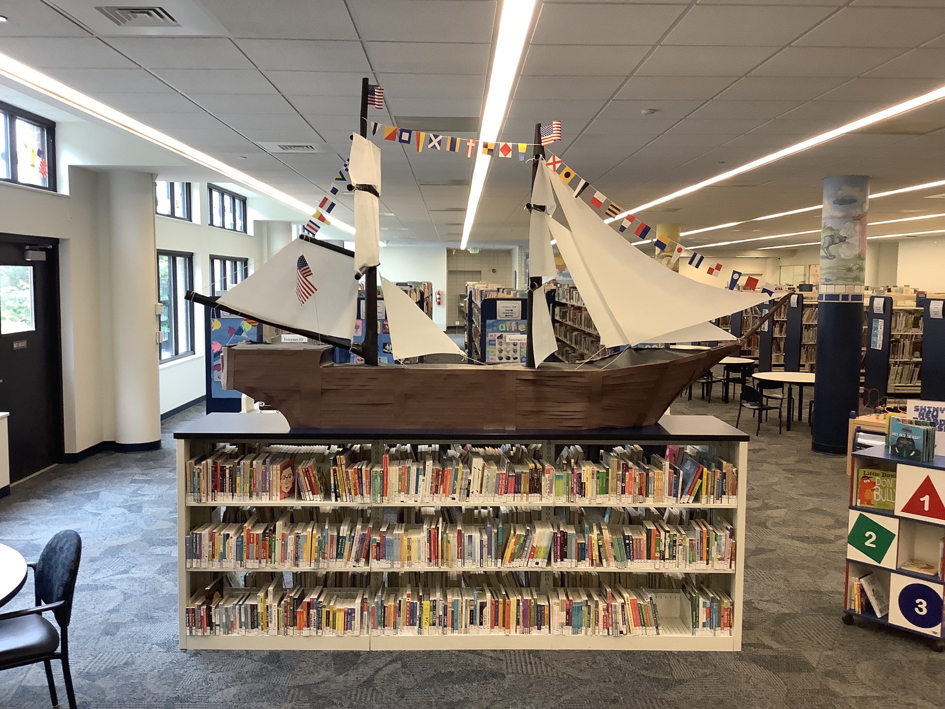 A huge brigantine made of paper and cardboard sitting atop a bookshelf