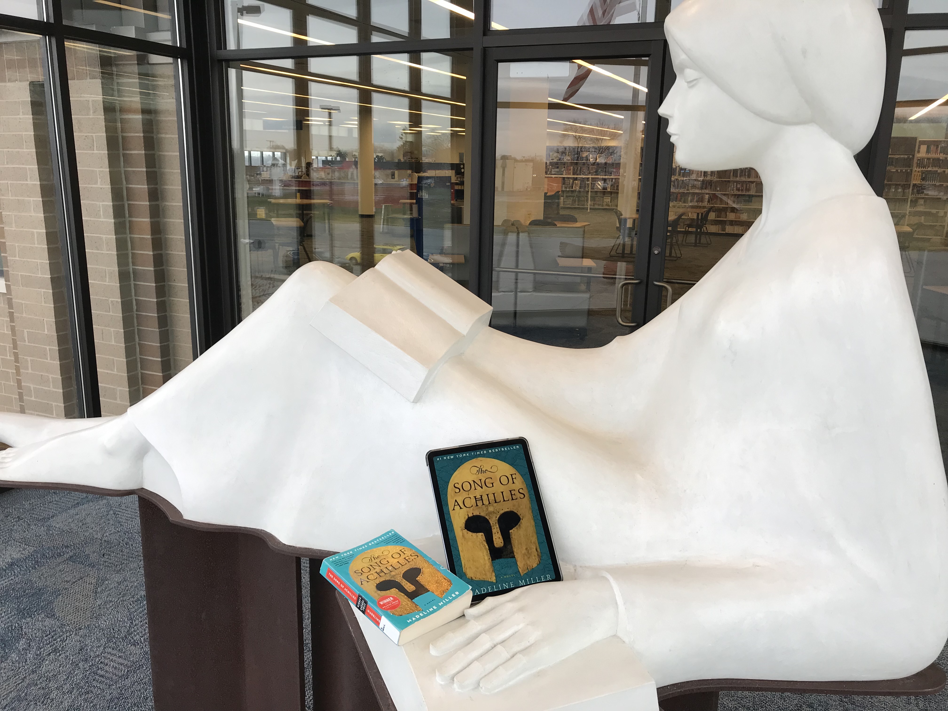 The Reader statue with a paper copy of a book and an ebook on a tablet