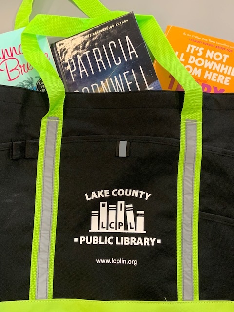 Black tote with neon green handles. Books are popping out the top
