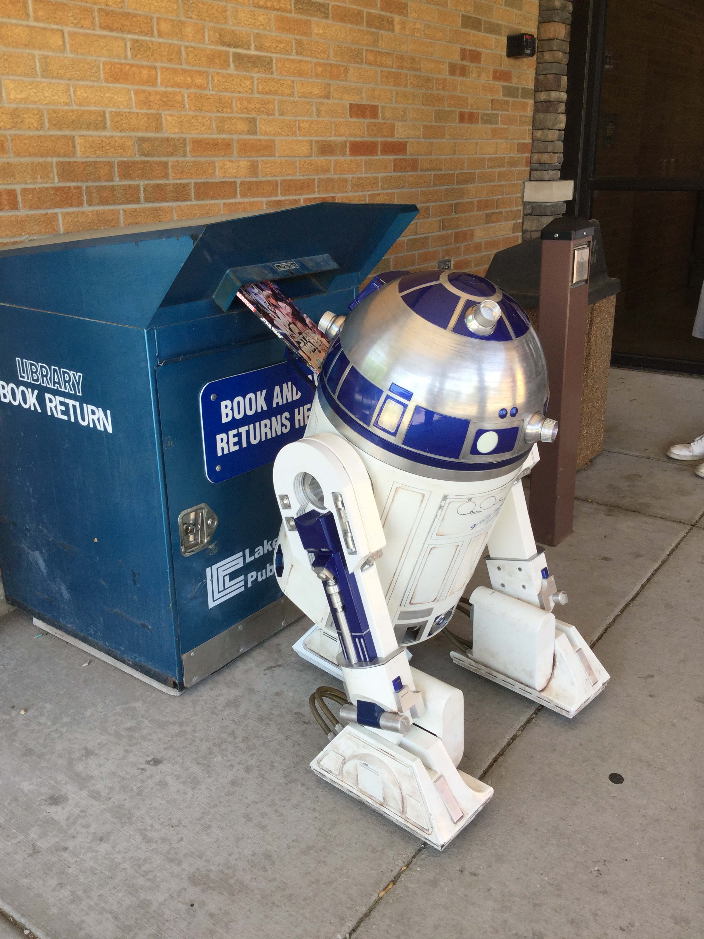 R2D2 pushes a star wars book into a book drop outside Munster Branch