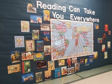 Display case with a map and settings of books marked with pins and yarn