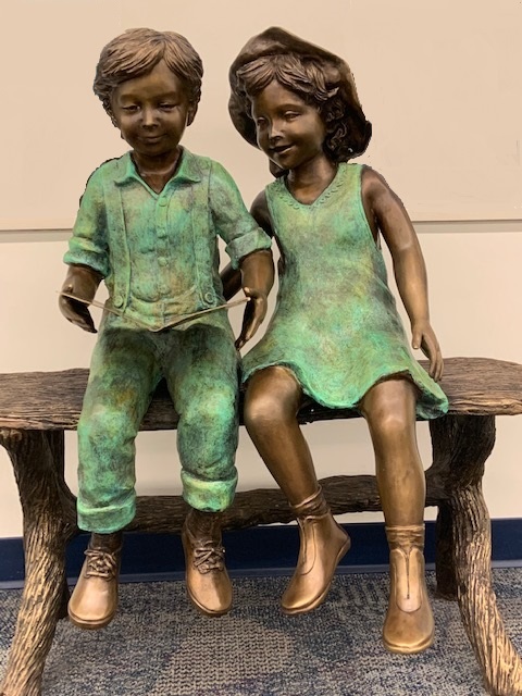 Bronze statue of two children reading on a bench