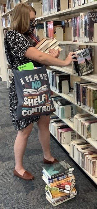 Woman taking many books from a shelf